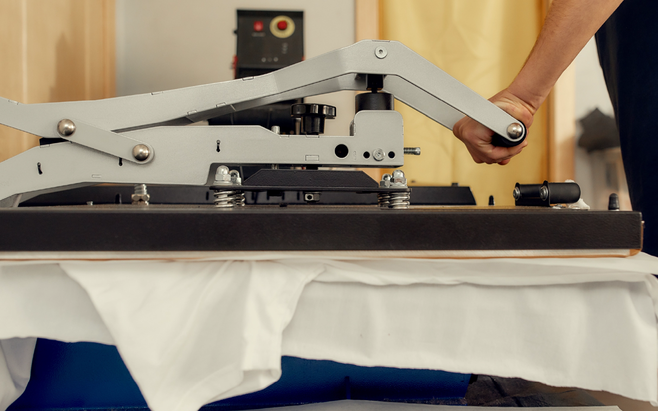 Cropped shot of male worker using heat press transfer machine for printing t-shirt