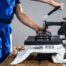 Print technician pressing down the handle of a heat press machine onto a custom printed white t-shirt, demonstrating the professional heat press printing process for custom apparel orders at The Logo Store in Austin TX