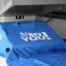 Finished custom heat press printed blue t-shirt displaying a bold white graphic design fresh off the heat press machine, showing the vibrant and sharp results of professional custom heat press printing services for branded apparel at The Logo Store in Austin TX