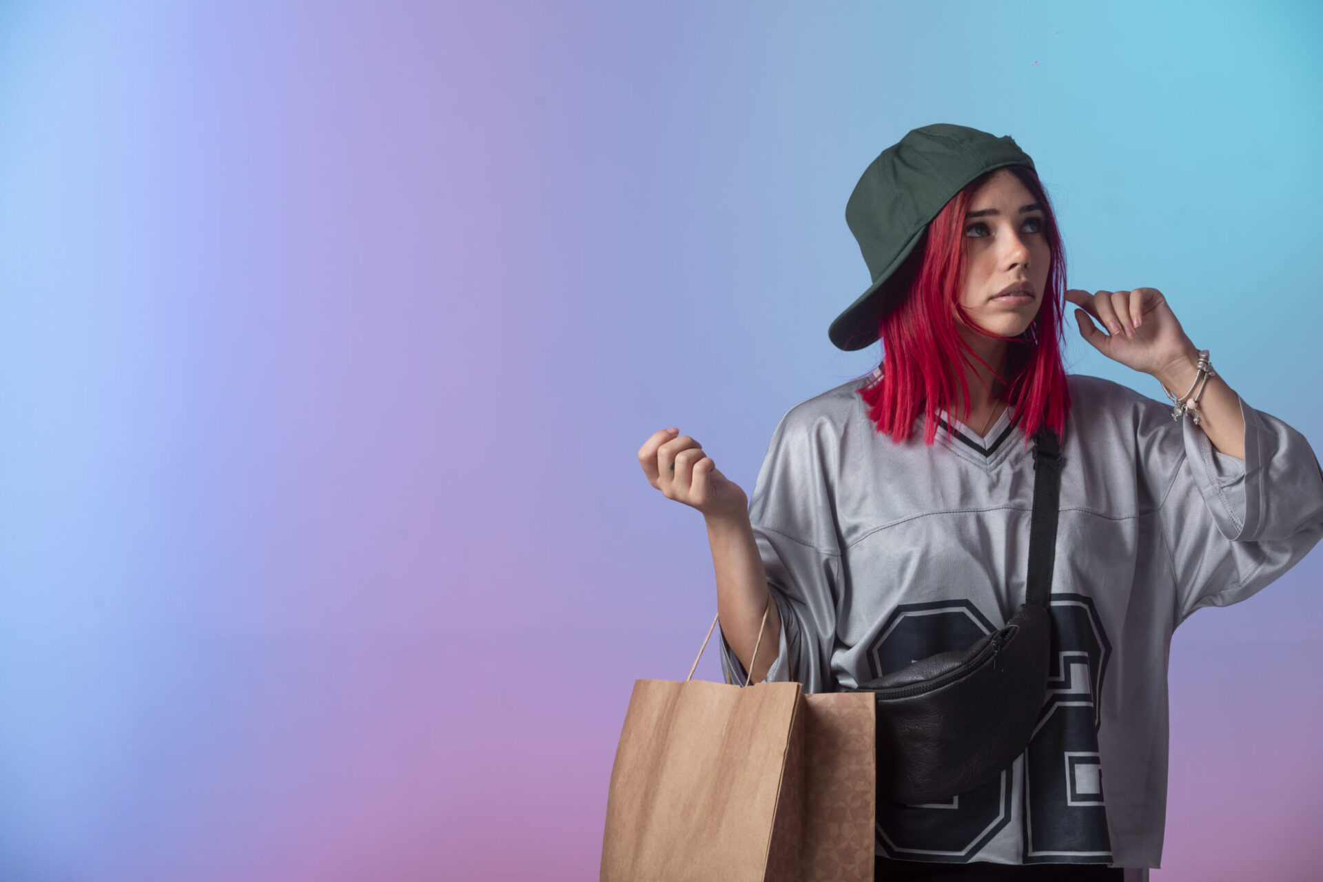 Young woman wearing a custom printed jersey and snapback cap while carrying branded shopping bags, representing the target customer for a new clothing brand — a key consideration when learning how to start a clothing brand in 2026
