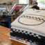 Stack of freshly printed custom t-shirts on the counter at an Austin print shop, ready for F1 race weekend.