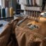 Multi-needle embroidery machine stitching a mountain logo onto a brown duck-canvas work jacket in an Austin shop